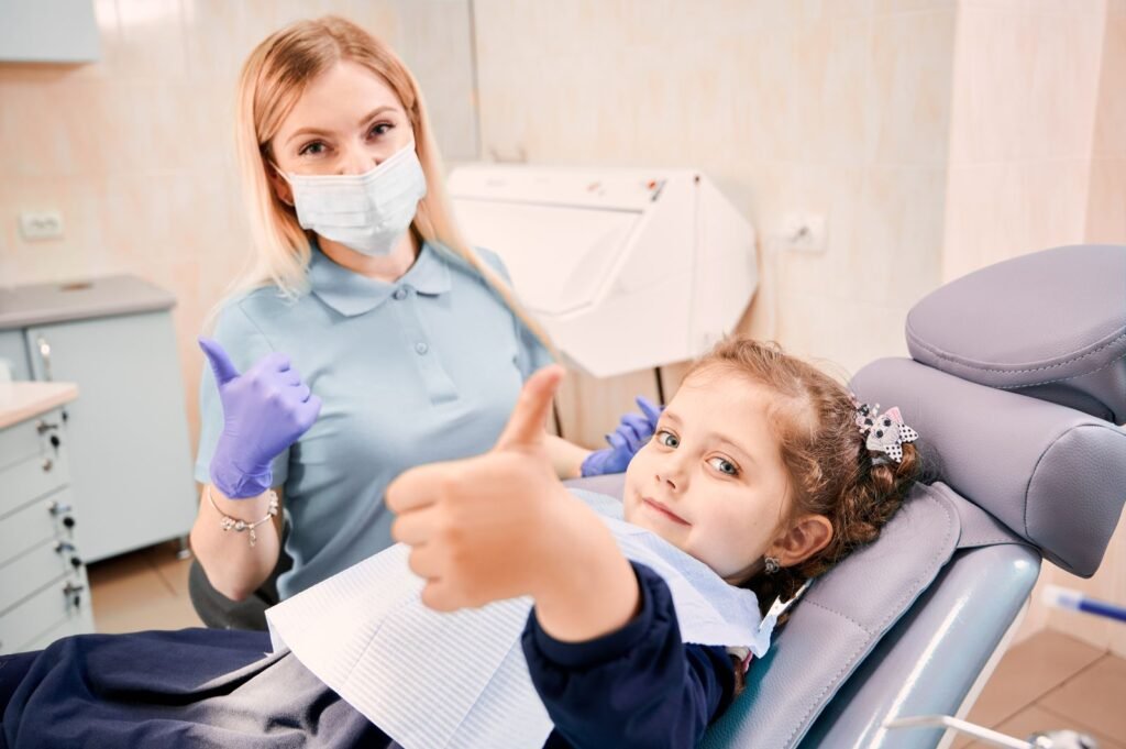 Dentista y niña con el pulgar arriba tras una revisión