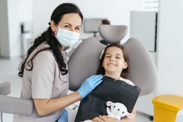 Niña sonriendo en el sillón del dentista durante una revisión infantil