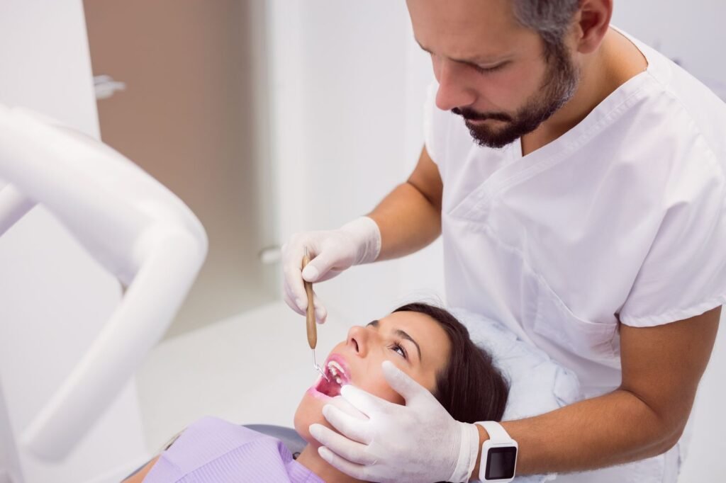 Dentista revisando las encías de una paciente con un espejo dental